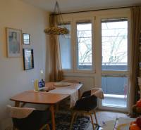 Dining area in a 3-room apartment with carpet decor and glass doors to the balcony.