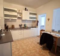 A kitchen in a family house with white cabinets, a table, and tiles.