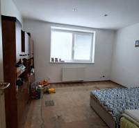 A room in a family house with a bed, furniture, and a wooden decor floor.