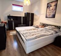Bedroom in a family house with wood-patterned flooring, a bed, and black furniture.
