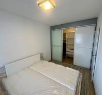Bedroom with a double bed, built-in wardrobe, and wooden decor flooring in a 2-room apartment.