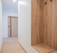 A hallway with built-in furniture in a 2-room apartment, light wooden floors, white walls.