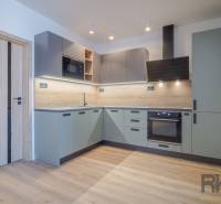 A kitchen in a 2-room apartment with wooden flooring and light gray cabinets.