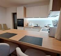 A kitchen in a 2-room apartment with built-in appliances and a wooden decor floor.