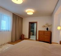Bedroom in a 2-room apartment with wooden decor, curtains, and light furniture.