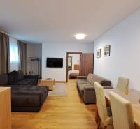 Living room with a sofa and TV, next to the dining table, floor with wood decor.