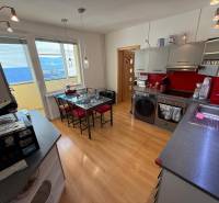 A kitchen in a 3-room apartment with a wooden decor floor and red accents.