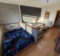 Living room with a sofa, bed, and wooden decor flooring in a three-room apartment.