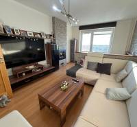Living room in a 3-room apartment with a comfortable sofa, wooden decor flooring, and a television.