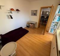 A room with a bed and storage shelves, a floor with a wooden decor in a 3-room apartment.