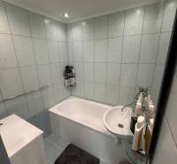 A bathroom with a bathtub, light tiles, and ceiling panel lighting in a 3-room apartment.