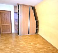 A room with a wooden decor floor, a built-in wardrobe, and wooden doors.