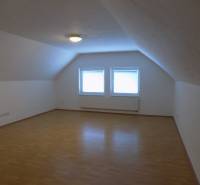 A white room with two windows and a wooden decor floor in a building.