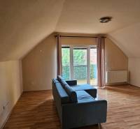 Interior of a building with wood-decor flooring, a sofa, and a balcony.