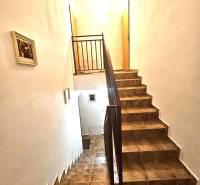 A staircase in a building with tiled cladding and railing, illuminated by white light.