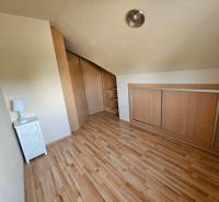 A room with a wooden decor floor, a built-in wardrobe, and a nightstand.