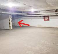 Underground parking area in the garage with a parking space by the wall and cars.