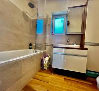 A bathroom in a 4-room apartment with a bathtub, sink, and floor with a wooden decor.