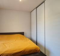 A bedroom in a 2-room apartment with white wardrobes and a yellow duvet.