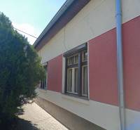 A family house in Nové Zámky with nets on the insulated facade and a tree by the sidewalk.