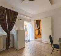 A room in a one-bedroom apartment with a tiled floor and dark curtains.