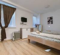 A room with beds, a television on the wall, and a floor with a wooden decor.