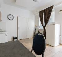 A kitchen in a one-room apartment with simple furnishings, floor with wood decor.