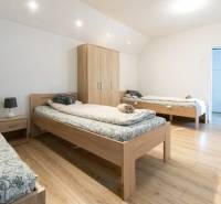 A bedroom with three beds, a wardrobe, and a wooden decor floor in a studio apartment.