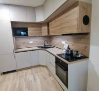 A kitchen in a studio apartment with a wooden decor floor and modern appliances.