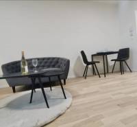 Living area in a one-room apartment with a sofa, table, and wooden decor flooring.