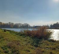 The river in Mostová surrounded by agricultural and forest land, the sun above the horizon.