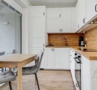 A kitchen with white cabinets, a wooden countertop, and a table in a studio apartment.