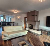 A spacious living room with a fireplace in a family house, light furniture, and a floor with a wood decor.