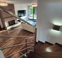 Living room with a fireplace and staircase in a family house, floor with wooden decor.