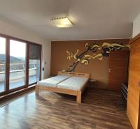 A room in a family house with a wooden decor floor, a double bed, and a terrace.