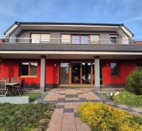 A family house in Krakovany on Vetrná Street, with a red facade and a garden.
