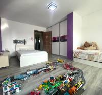 Children's room in a family house with a bed, toys, and a wooden decor floor.