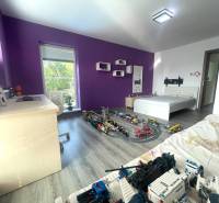 Children's room in a family house with purple walls, toys, and a wooden decor floor.