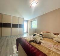 A bedroom in a family house with a wood-patterned floor, a built-in wardrobe, and plush toys.