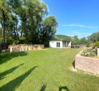 A garden at a family house in Melčice-Lieskové with wood and a shelter on the lawn.