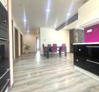 A kitchen in a family house with a wooden decor floor and purple chairs.