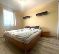 Bedroom in a family house with a bed, nightstand, and floor with wooden decor.