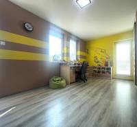 Children's room in a family house with a wooden decor floor and yellow stripes on the walls.
