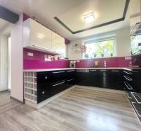 A kitchen with burgundy elements and a wooden decor floor in a family house.