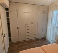 Bedroom with a white built-in wardrobe and a bed in a 3-room apartment with a wooden decor floor.