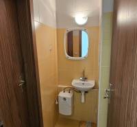 A bathroom in commercial premises with a sink and a mirror, tiled with light tiles.