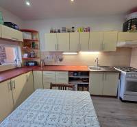 A kitchen in a 3-room apartment with a cream-colored kitchen unit and a wooden decor floor.