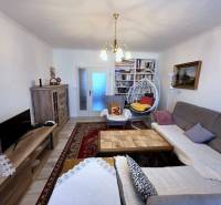 Living room in a three-room apartment with a wooden decor floor and bookshelves.