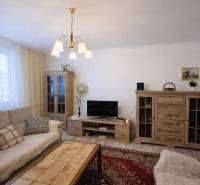 Living room in a three-room apartment with wooden decor and comfortable seating.