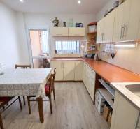 A kitchen in a 3-room apartment with white furniture and a wooden decor floor.